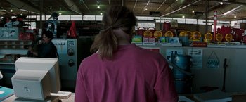 Movie still from “Heat” (1995), directed by Michael Mann – A woman with a ponytail is standing in a store; Medium shot, Over the shoulder angle