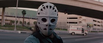 Movie still from “Heat” (1995), directed by Michael Mann – A person wearing a hockey mask on the side of the street; Close Up shot, Low angle