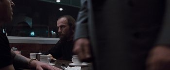 Movie still from “Heat” (1995), directed by Michael Mann – A man sitting at a table with a cup of coffee; Medium shot, Over the shoulder angle