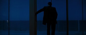 Movie still from “Heat” (1995), directed by Michael Mann – A man standing in front of a window at night; Wide shot, Over the shoulder angle
