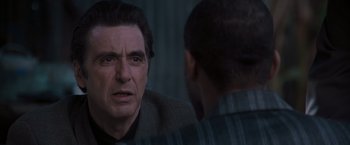 Movie still from “Heat” (1995), directed by Michael Mann – A man looking into a mirror while talking to another man; Close Up shot, Over the shoulder angle