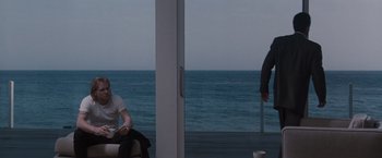 Movie still from “Heat” (1995), directed by Michael Mann – Two people sitting on a couch near the ocean; Wide shot, Over the shoulder angle
