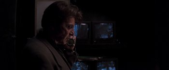 Movie still from “Heat” (1995), directed by Michael Mann – An older man talking on a phone in front of a television; Close Up shot, Low angle