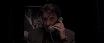 Movie still from “Heat” (1995), directed by Michael Mann – A man talking on a phone while wearing a suit and tie; Close Up shot, Low angle