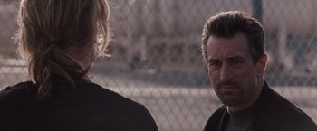 Movie still from “Heat” (1995), directed by Michael Mann – A man and a woman standing next to each other in front of a chain link fence; Close Up shot, Over the shoulder angle