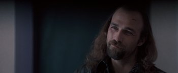 Movie still from “Heat” (1995), directed by Michael Mann – A man with long hair and a goatee stares at the camera; Close Up shot, Over the shoulder angle