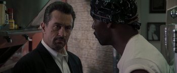 Movie still from “Heat” (1995), directed by Michael Mann – A man in a suit and a man in a head scarf; Close Up shot, Over the shoulder angle