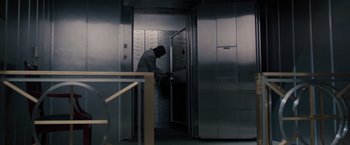 Movie still from “Heat” (1995), directed by Michael Mann – A man is looking into an elevator with many boxes; Wide shot, High angle