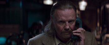 Movie still from “Heat” (1995), directed by Michael Mann – An older man talking on a phone while wearing a suit; Close Up shot, Low angle