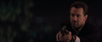 Movie still from “Heat” (1995), directed by Michael Mann – A man in a suit and tie holding a gun; Close Up shot, Low angle
