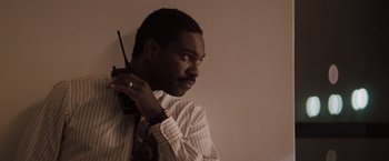 Movie still from “Heat” (1995), directed by Michael Mann – A man in a dress shirt and tie holding a walkie talkie; Close Up shot, Low angle