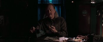 Movie still from “Heat” (1995), directed by Michael Mann – A man sitting at a table with papers in front of him; Close Up shot, Low angle