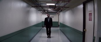 Movie still from “Heat” (1995), directed by Michael Mann – A man in a suit and tie walking down a hallway; Wide shot, Low angle