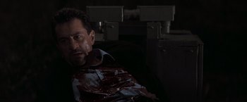 Movie still from “Heat” (1995), directed by Michael Mann – A man with a bunch of blood on his face; Close Up shot, High angle