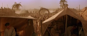 Movie still from “Stargate” (1994), directed by Roland Emmerich – A group of people standing next to each other in a field; Extreme Wide shot, High angle