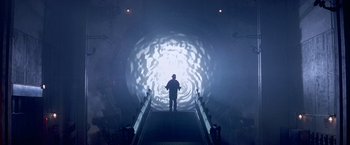 Movie still from “Stargate” (1994), directed by Roland Emmerich – A man standing on top of an escalator in a tunnel; Wide shot, Low angle