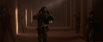 Movie still from “Stargate” (1994), directed by Roland Emmerich – A man in a military uniform adjusts his hat; Wide shot, Low angle