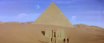 Movie still from “Stargate” (1994), directed by Roland Emmerich – Two people are standing in front of a pyramid; Extreme Wide shot, Low angle