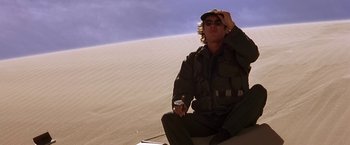 Movie still from “Stargate” (1994), directed by Roland Emmerich – A man sitting on the ground in the desert; Medium shot, High angle