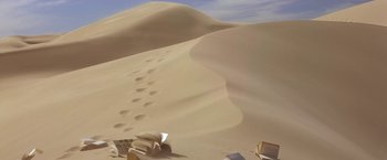 Movie still from “Stargate” (1994), directed by Roland Emmerich – A book is sitting on the sand near a trail of footprints; Extreme Wide shot, High angle