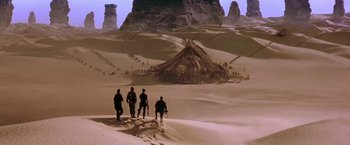 Movie still from “Stargate” (1994), directed by Roland Emmerich – A group of people standing on top of a sand dune; Extreme Wide shot, High angle