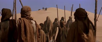 Movie still from “Stargate” (1994), directed by Roland Emmerich – A group of people in the desert walking up a sand dune; Wide shot, Low angle