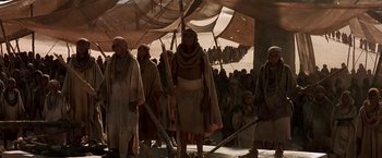 Movie still from “Stargate” (1994), directed by Roland Emmerich – A group of people standing in front of a tent; Wide shot, High angle