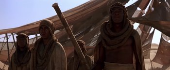 Movie still from “Stargate” (1994), directed by Roland Emmerich – A group of men standing next to each other; Medium shot, Low angle