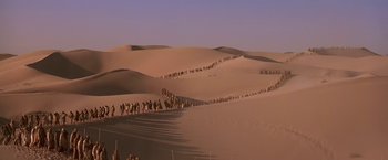 Movie still from “Stargate” (1994), directed by Roland Emmerich – A large group of people walking across the desert; Extreme Wide shot, High angle