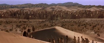 Movie still from “Stargate” (1994), directed by Roland Emmerich – A group of people standing on top of a sand dune; Extreme Wide shot, High angle