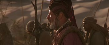 Movie still from “Stargate” (1994), directed by Roland Emmerich – An old man with a long beard and a red turban; Close Up shot, Over the shoulder angle