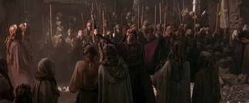 Movie still from “Stargate” (1994), directed by Roland Emmerich – A group of people in medieval clothing with wooden spears; Wide shot, High angle