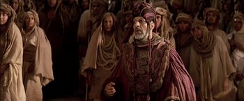 Movie still from “Stargate” (1994), directed by Roland Emmerich – An old man wearing a turban in front of a group of people; Medium shot, High angle