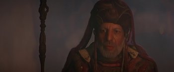 Movie still from “Stargate” (1994), directed by Roland Emmerich – An old man with a long beard wearing a hat; Close Up shot, Low angle