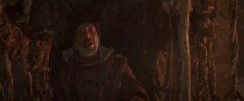 Movie still from “Stargate” (1994), directed by Roland Emmerich – An old man with a beard is wearing a hat; Close Up shot, Over the shoulder angle