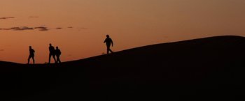 Movie still from “Stargate” (1994), directed by Roland Emmerich – A person walking up a hill at sunset; Extreme Wide shot, Low angle