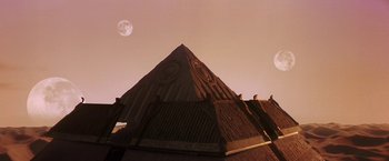 Movie still from “Stargate” (1994), directed by Roland Emmerich – A building that has a clock on the top of it; Extreme Wide shot, Low angle