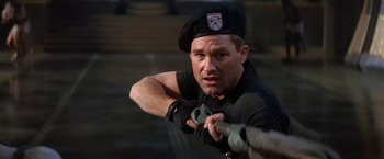 Movie still from “Stargate” (1994), directed by Roland Emmerich – A man holding a baseball bat while wearing a hat; Close Up shot, Low angle