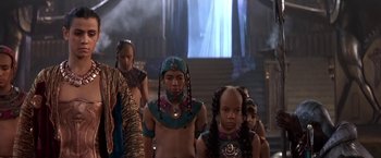 Movie still from “Stargate” (1994), directed by Roland Emmerich – A group of young people in costumes in a room; Medium shot, Low angle