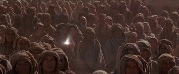 Movie still from “Stargate” (1994), directed by Roland Emmerich – A group of people gathered together in a field; Extreme Wide shot, High angle