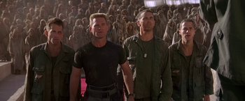 Movie still from “Stargate” (1994), directed by Roland Emmerich – A group of men standing next to each other in front of a crowd; Medium shot, Low angle