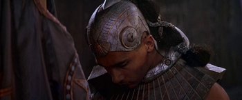 Movie still from “Stargate” (1994), directed by Roland Emmerich – A person wearing a metal helmet; Close Up shot, Over the shoulder angle