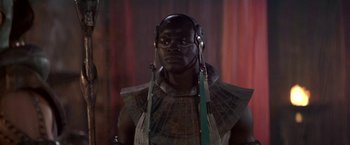 Movie still from “Stargate” (1994), directed by Roland Emmerich – A man wearing headphones is standing in front of a curtain; Close Up shot, Low angle