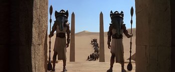 Movie still from “Stargate” (1994), directed by Roland Emmerich – A group of men standing next to each other in a desert; Wide shot, Low angle