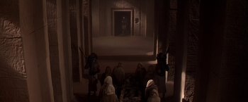 Movie still from “Stargate” (1994), directed by Roland Emmerich – A group of people sitting in front of an open door; Wide shot, High angle