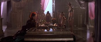 Movie still from “Stargate” (1994), directed by Roland Emmerich – A group of people standing around a table with food on it; Wide shot, High angle