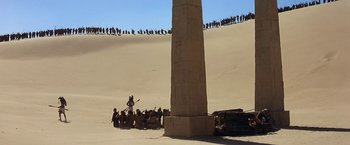 Movie still from “Stargate” (1994), directed by Roland Emmerich – A group of people standing around a tall pillar; Extreme Wide shot, Low angle