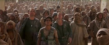 Movie still from “Stargate” (1994), directed by Roland Emmerich – A large group of people in the middle of a field; Medium shot, Low angle