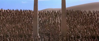 Movie still from “Stargate” (1994), directed by Roland Emmerich – A crowd of people standing in front of a wall; Extreme Wide shot, High angle