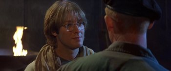 Movie still from “Stargate” (1994), directed by Roland Emmerich – A man wearing glasses talking to another man; Close Up shot, Over the shoulder angle